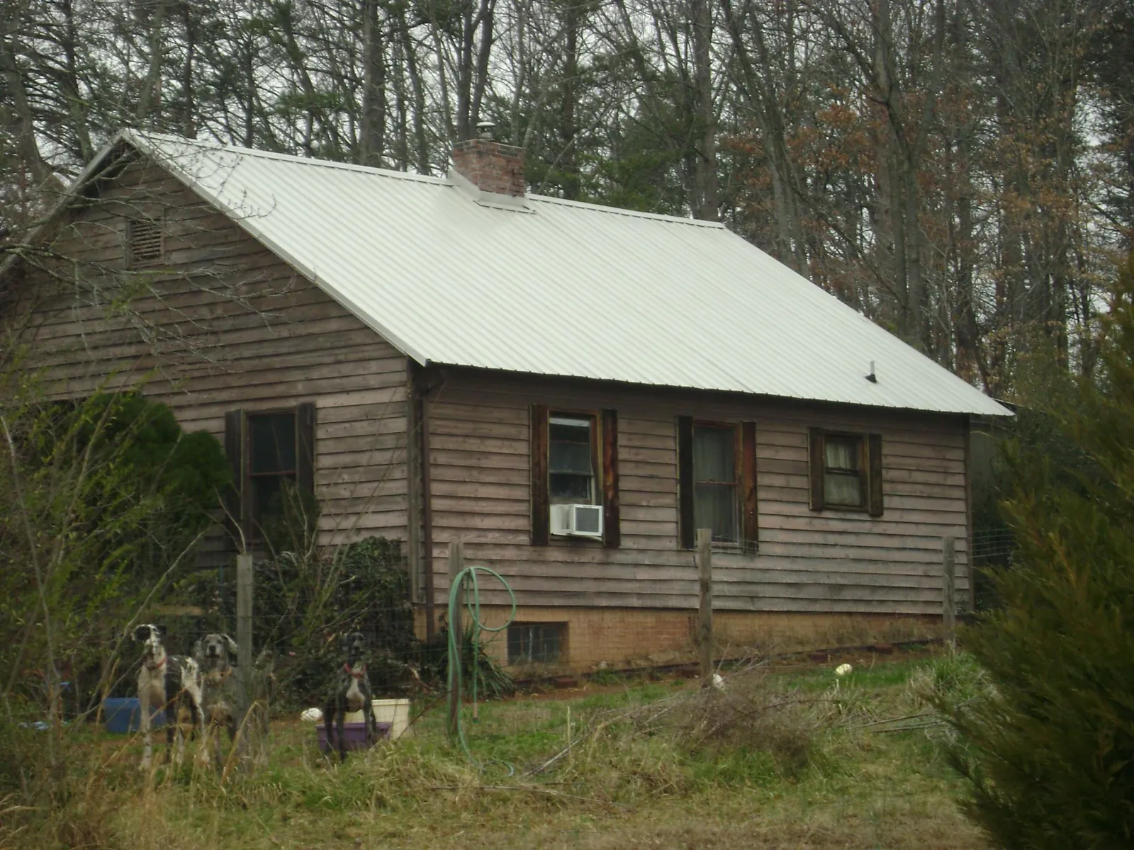 White metal roof on an old wood sided farmhouse, from a Metal Roof Installation job in Midland
